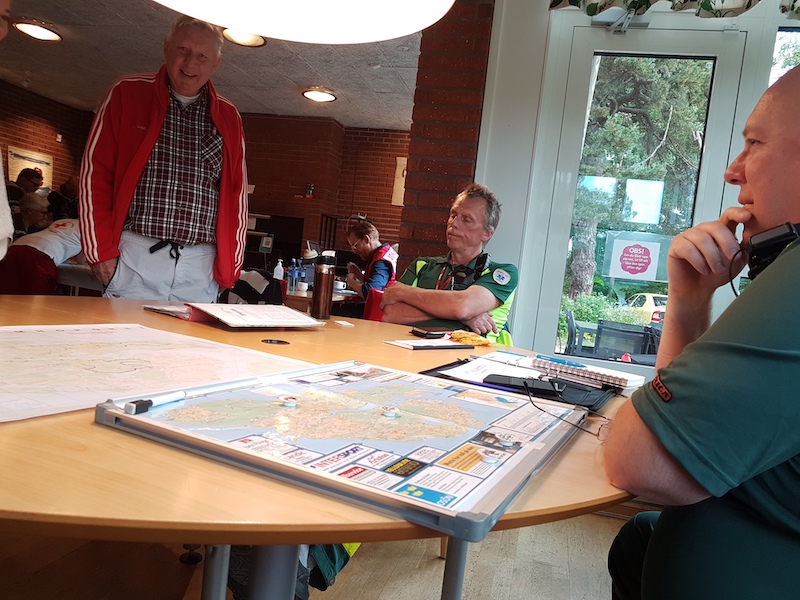 Ambulanspersonal och läkare vid ett eget bord på lagom höravstånd från sambandspersonalen